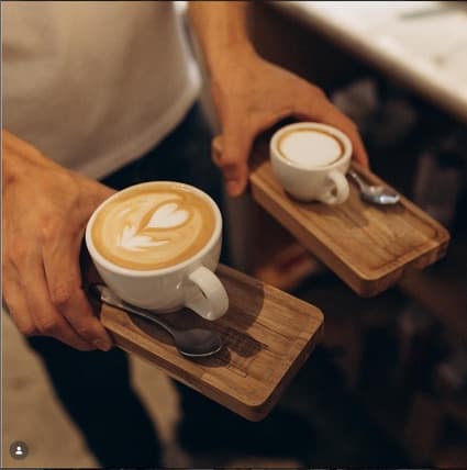 Duas xícaras de café servidas em bandejas de madeira