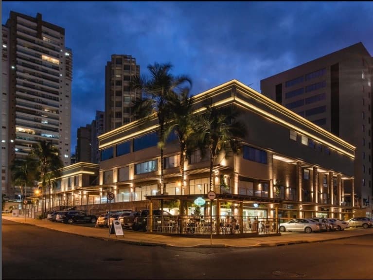 Fachada do Fiusa Center iluminada à noite, com palmeiras e prédios ao redor
