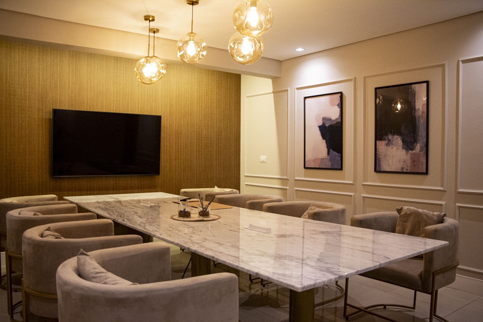 Sala de reunião do Ypê Coworking com mesa de mármore, poltronas e TV